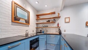A modern kitchen with blue cabinets, a black countertop, and a wooden backsplash. - Comfortable Modern Condo near Downtown (Friday Harbor)