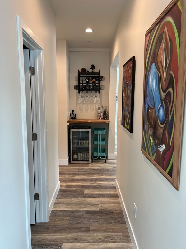 A hallway with a wooden floor, a refrigerator, a shelf with bottles and glasses, and a painting on the wall. - Mountain Property with amazing views and close to Bozeman (Bozeman)