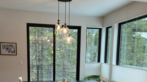 Een moderne keuken met een marmeren aanrecht, een zwarte eettafel en hanglampen.