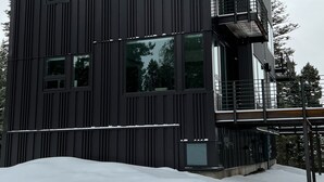 Een modern, meerlaags gebouw met een donkere gevel en grote ramen.