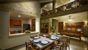 A dining area with a long table set for four, surrounded by wooden chairs. A kitchen is visible in the background with modern appliances. - villa deh simba at seminyak oberoi  (Seminyak)