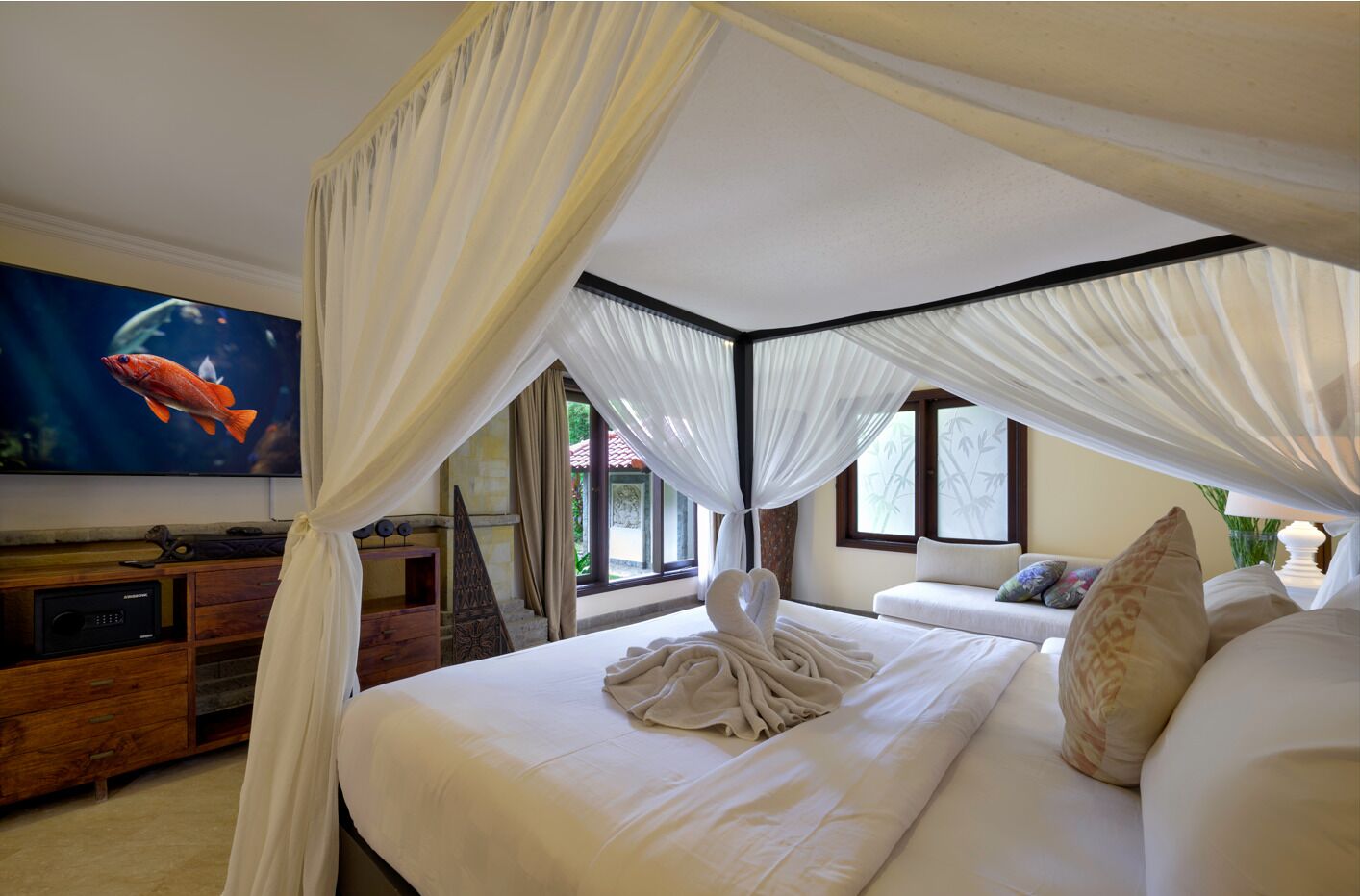Un dormitorio con cama con dosel, televisor de pantalla plana y cómoda de madera.
