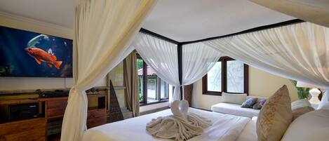 Un dormitorio con cama con dosel, televisor de pantalla plana y cómoda de madera.