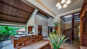 A spacious indoor area with a wooden bench, a dining table, and a decorative vase with flowers. - villa deh simba at seminyak oberoi  (Seminyak)