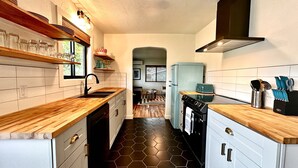 Una cocina compacta con encimeras de madera, horno integrado y tostadora. Hay una ventana que proporciona luz natural y vistas al exterior.
