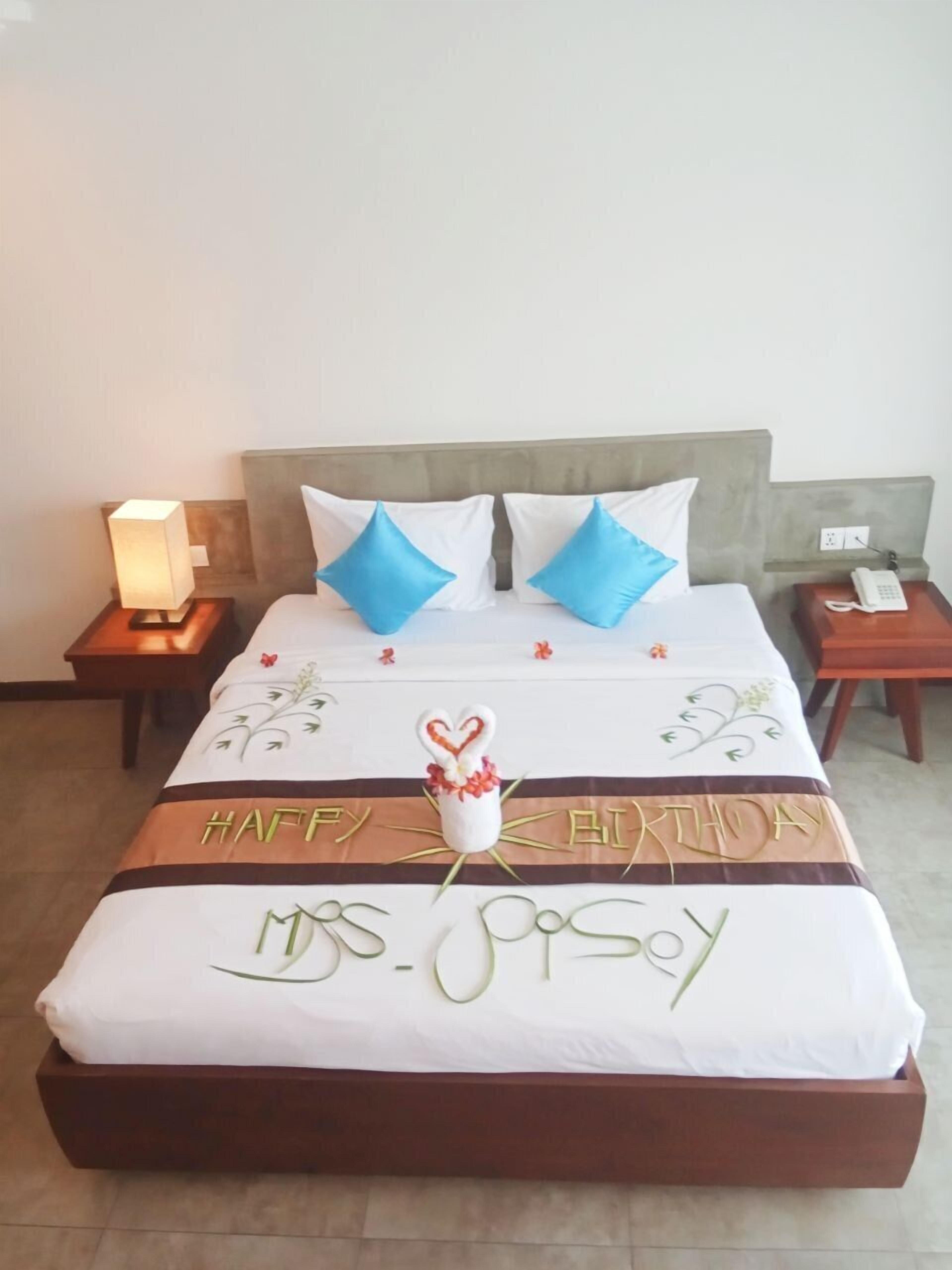 A hotel room with a bed, a nightstand with a lamp, and a bedside table with a phone.