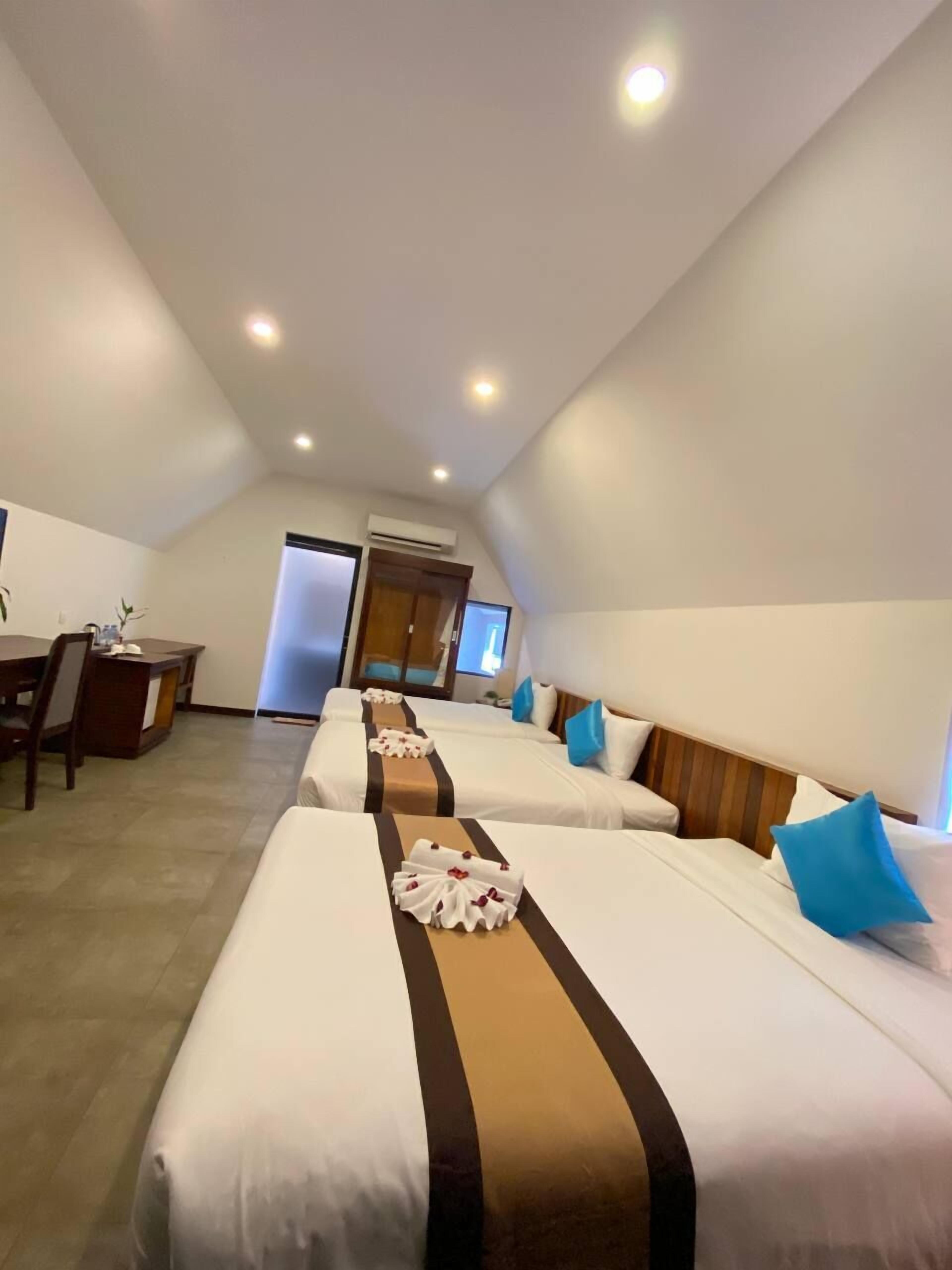 Une chambre d’hôtel avec deux lits, un bureau et une porte donnant sur un balcon.
