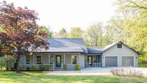 Ein zweistöckiges Haus mit Veranda, Garage und gepflegtem Rasen.