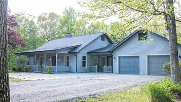 Een huis met twee verdiepingen, een veranda, een garage en een oprit met grind.