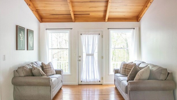 Ein Zimmer mit zwei Sofas, einer Holzbalkendecke und einer Tür mit Vorhängen.
