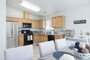 Una cocina moderna con armarios de madera, refrigerador, estufa, microondas y cartel de barra de café.