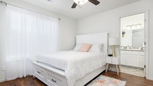 A bedroom with a bed, a nightstand, a lamp, a dresser, and a window with curtains. - Bright & Comfy House Near NAS with Free Parking (Armona)