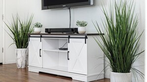 A white entertainment unit with a flat-screen TV mounted above it, flanked by two potted plants. - Bright & Comfy House Near NAS with Free Parking (Armona)