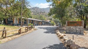 Un motel amb façana de pedra, carrer d'accés pavimentat i tanca de fusta.