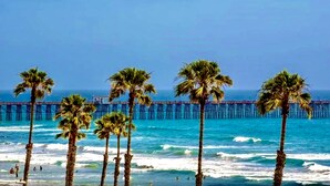 A beach with palm trees and a pier extending into the ocean.