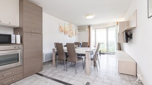 Et moderne køkken med spiseplads, med et stort bord, stole og indbyggede apparater.