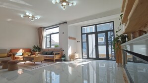 A spacious living room with a large window, a sofa, a coffee table, and a staircase. - Shanyutianyuan (Huairou)