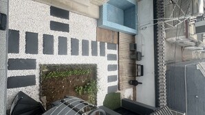 A modern outdoor space with a stone wall, a small garden area, and a metal staircase leading to an upper level. - Shanyutianyuan (Huairou)