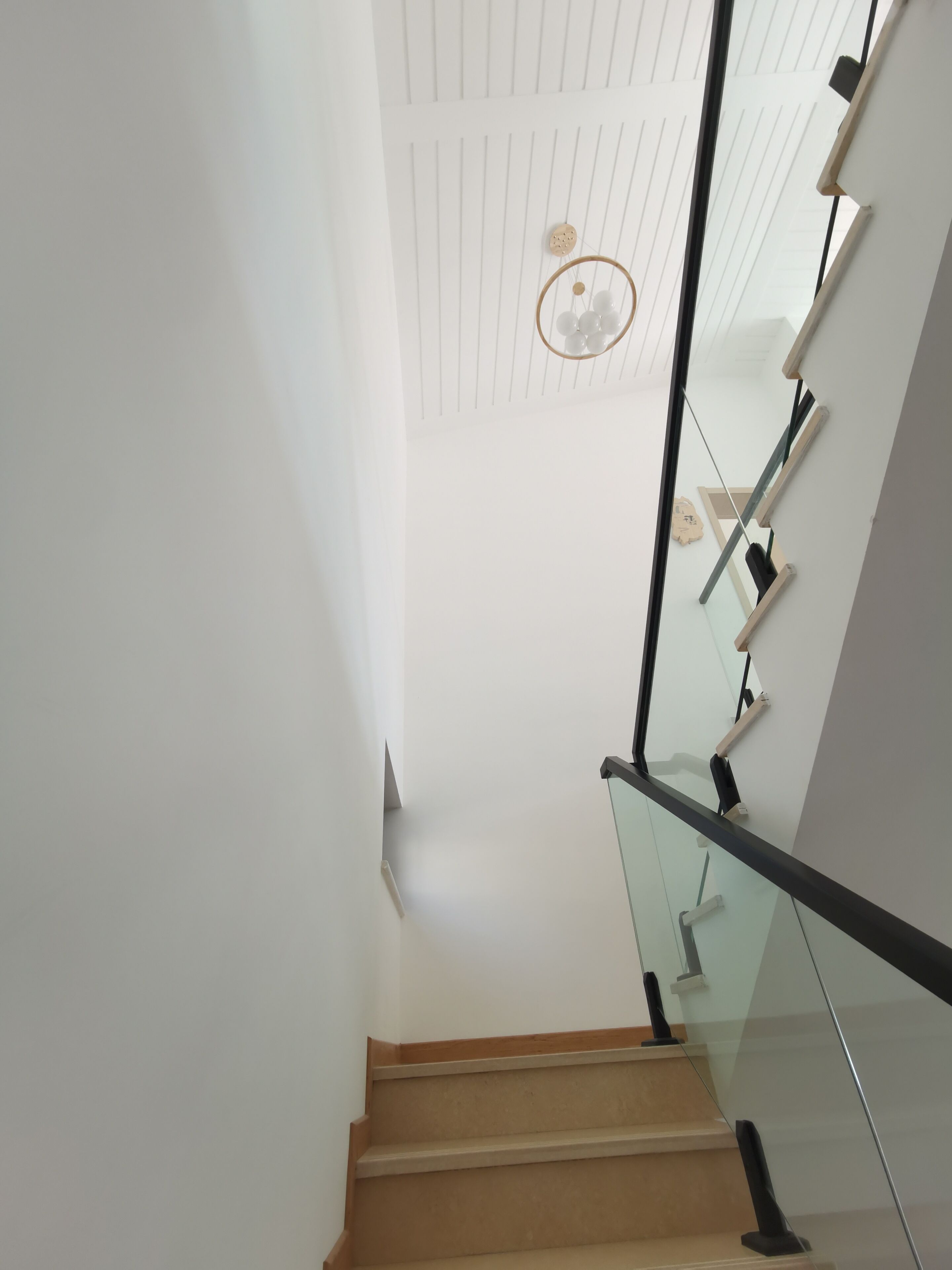 Una escalera moderna con barandillas de cristal y peldaños de madera.