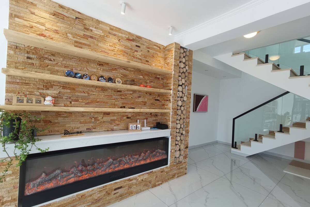 Un intérieur moderne avec une cheminée en pierre, des étagères en bois et un escalier.