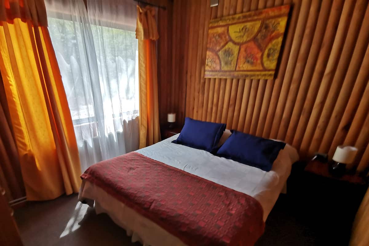 Ein Hotelzimmer mit Bett, Vorhängen, einem Nachttisch und einer Wanddekoration.