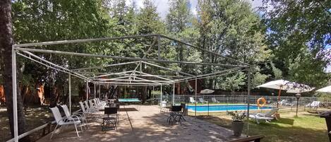 An outdoor patio area with a pool, lounge chairs, and a covered seating area.