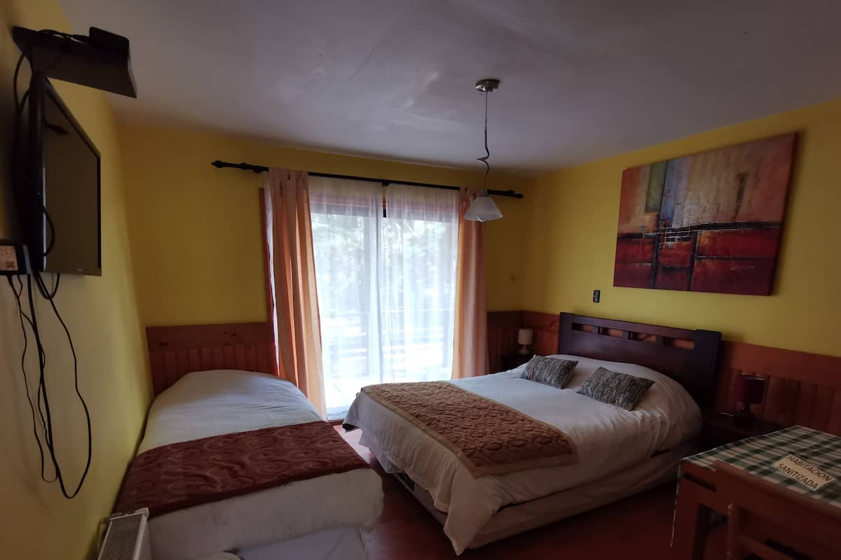 Ein Zimmer mit zwei Betten, einem Schreibtisch, einem Gemälde und einem Deckenventilator.