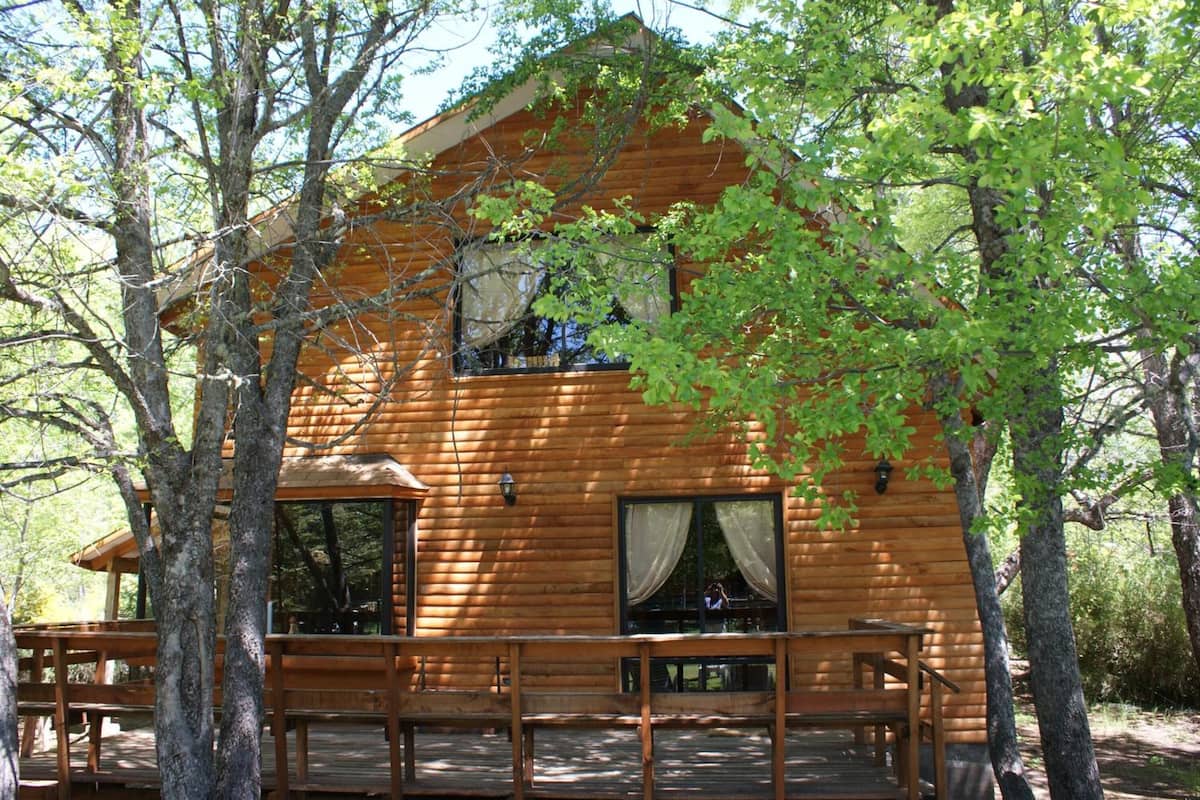 Eine Holzhütte mit einer Terrasse, umgeben von Bäumen.
