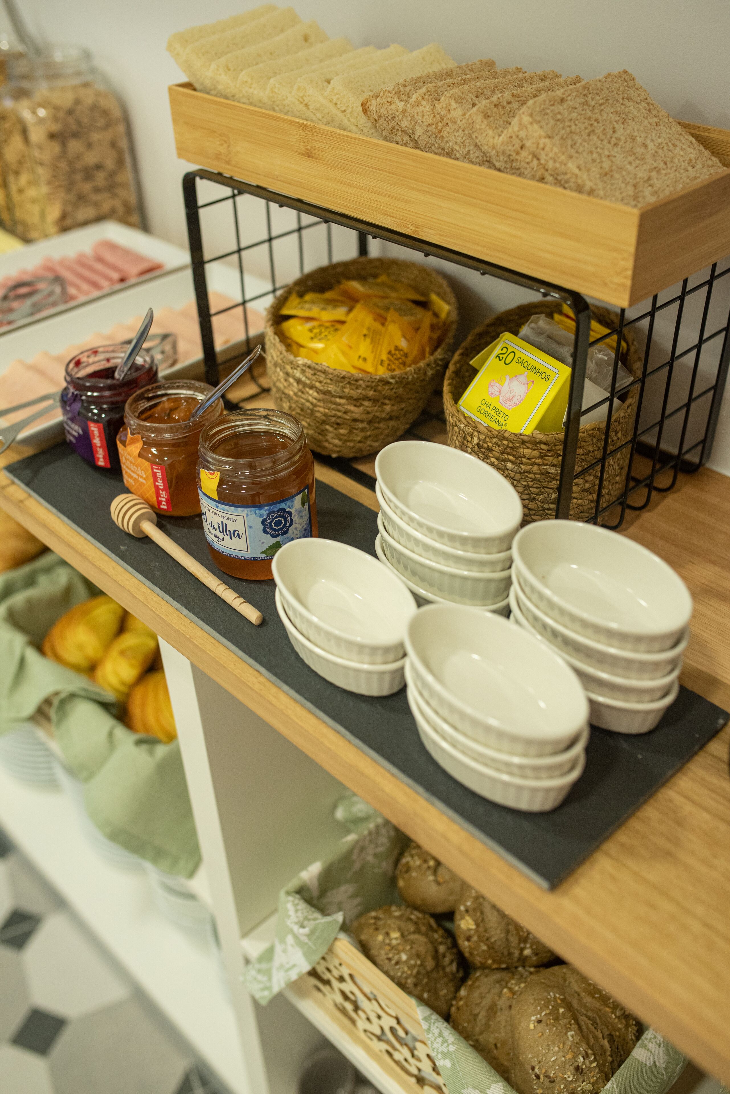 A breakfast buffet with bread, jams, honey, and bowls.