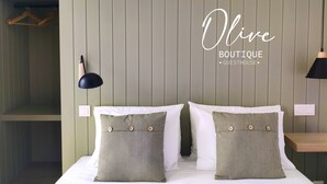 A hotel room with a bed, two pillows, a headboard, and a wall-mounted lamp. - Olive Boutique Guesthouse  (Vila Franca do Campo)