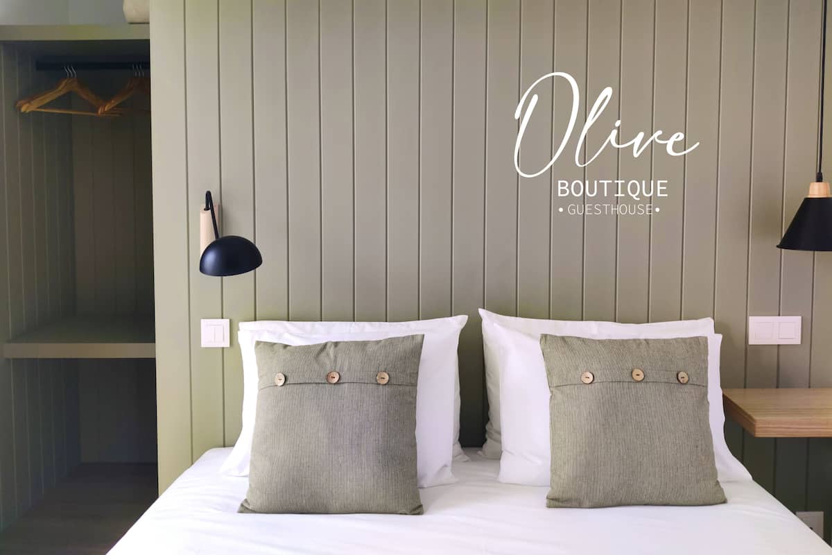 Ein Hotelzimmer mit einem Bett, zwei Kissen, einem Kopfteil und einer Wandlampe.