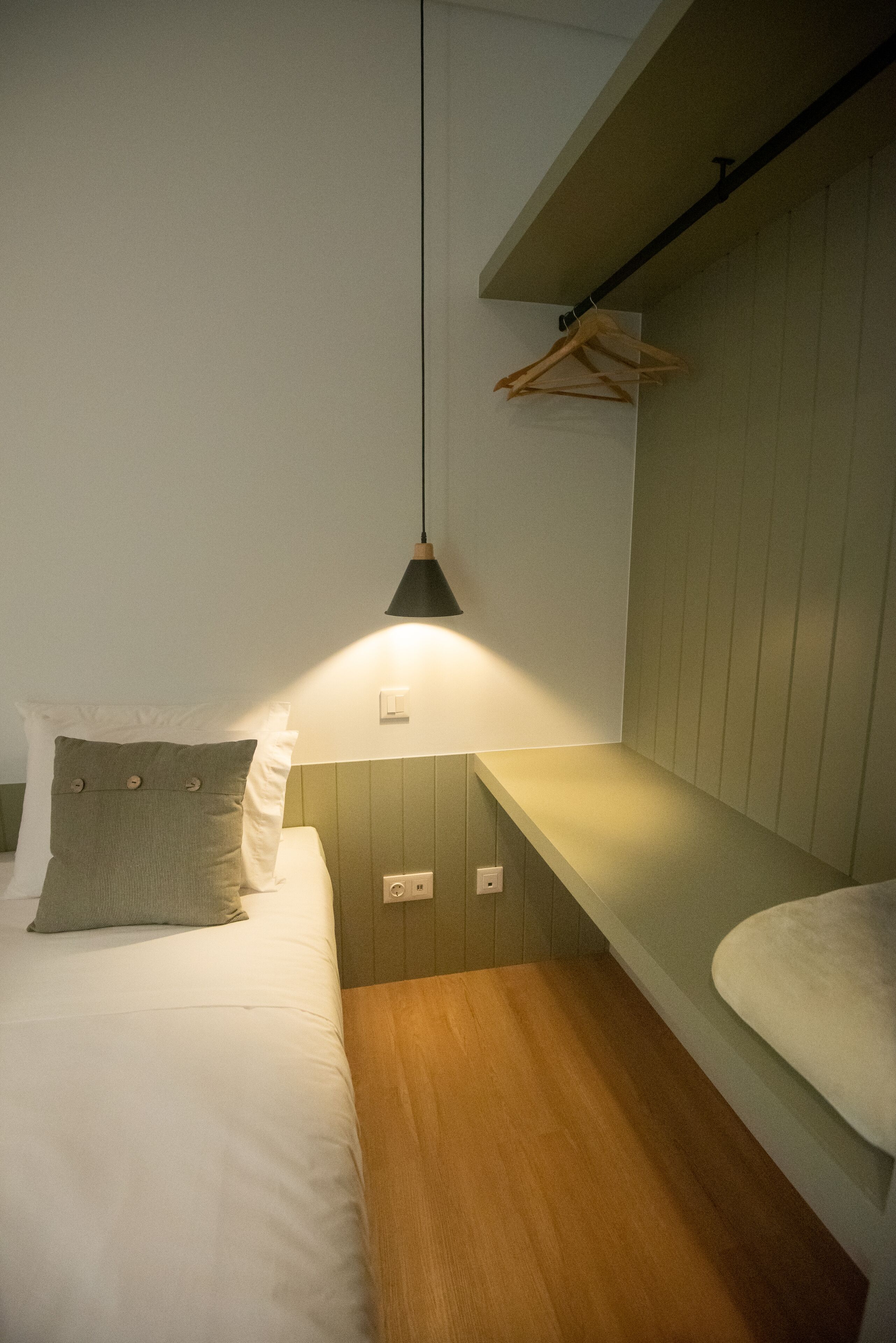 Ein Schlafzimmer mit Bett, einer Hängelampe und Holzboden.