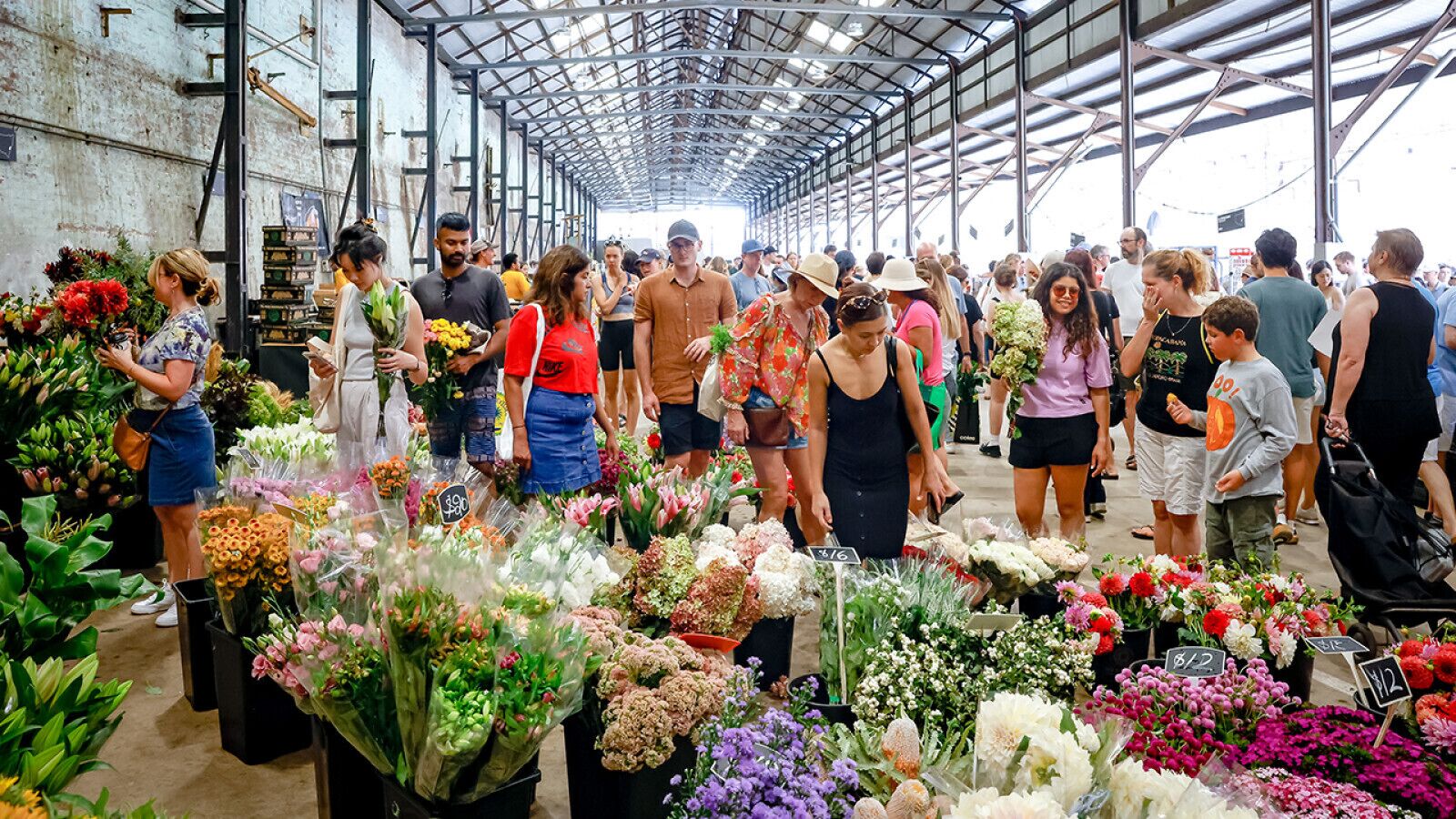 A large indoor market with various flowers on display.