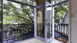 Eine Glastür führt zu einem Balkon mit Metallgeländer.