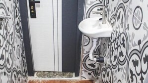Un baño con inodoro blanco, lavamanos y paredes con diseño.