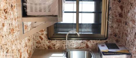 Una cocina compacta con ventana, un lavamanos de acero inoxidable y una encimera.