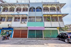 A multi-story building with a central entrance, large windows, and a variety of door types including metal gates and a sliding door. - Hotel O Hana StayNearNagoya Hill Mall (Batam)