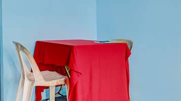 A small table with a red tablecloth, a plastic chair, and a blue wall in the background.