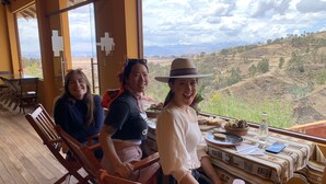 Un comedor con muebles de madera y una mesa dispuesta para una comida, con vistas a un paisaje montañoso.