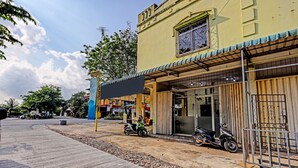 A building with a yellow facade, a covered entrance, and a parked scooter. - Hotel O Aulia Homestay Syariah (Batam)