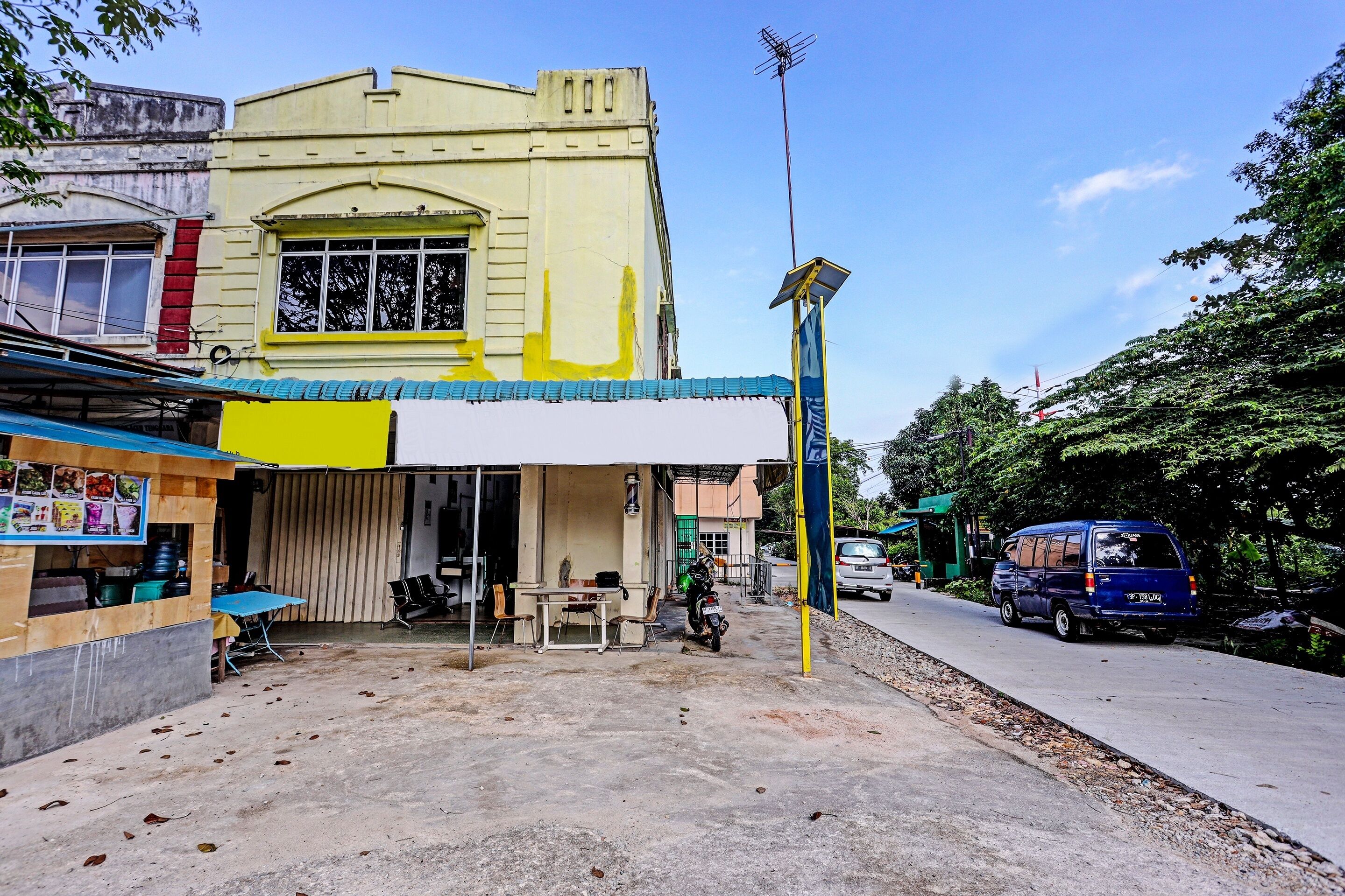 A building with a yellow facade, a blue awning, and a solar panel on the roof.