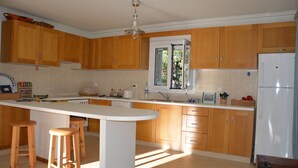 Une cuisine avec des meubles de rangement en bois, un plan de travail blanc et un îlot central intégré avec des tabourets.