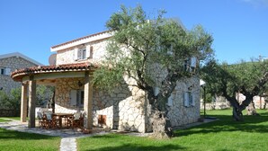 Une maison en pierre dotée d’un patio couvert et d’un espace extérieur aménagé pour s’asseoir.