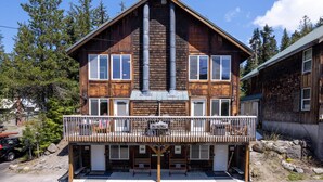 A two-story wooden house with a balcony, large chimneys, and a garage.