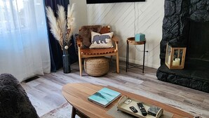Un salon équipé d’un téléviseur à écran plat, d’une cheminée en pierre, d’un canapé, d’une table basse et d’un fauteuil d écoratif.