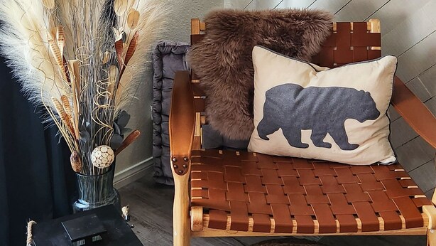Un coin salon accueillant avec un banc en osier, un pouf en osier, une petite lanterne et des plantes décoratives.