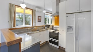 A modern kitchen with white cabinets, a microwave, an oven, and a refrigerator. - Spacious, Welcoming, and Secure (Hamilton)