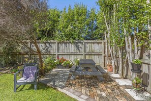 A backyard with a picnic table, a chair, a brick patio, and a wooden fence. - Spacious, Welcoming, and Secure (Hamilton)