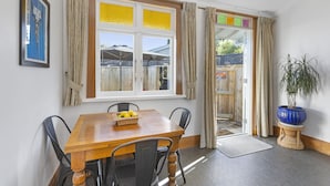 A dining area with a wooden table, four chairs, a basket of lemons, and a potted plant. - Spacious, Welcoming, and Secure (Hamilton)
