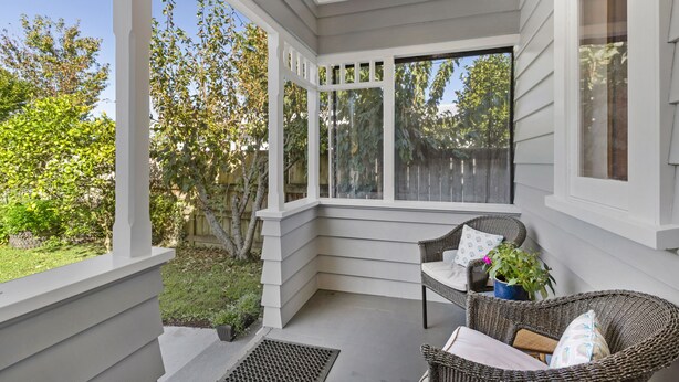 A covered porch with wicker furniture, a potted plant, and a view of the yard. - Spacious, Welcoming, and Secure (Hamilton)